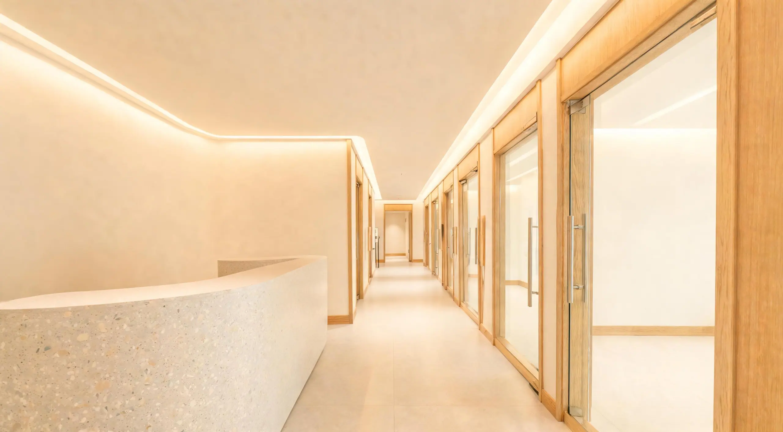 A finished medical office corridor with a terrazzo reception counter and white oak trim